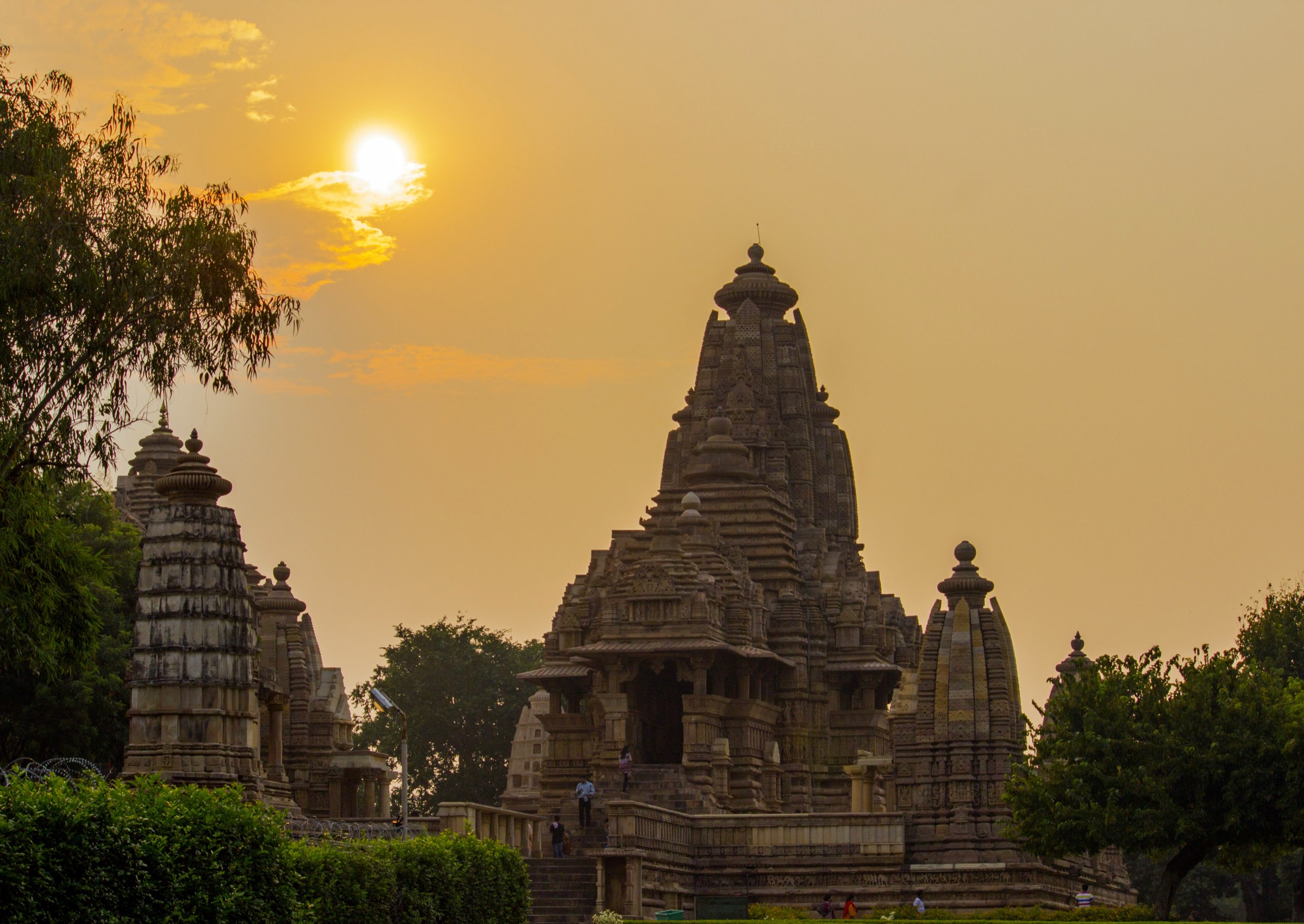 A sandstone temple complex silhouetted against a golden sunset sky